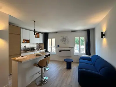 a living room with a blue couch and a kitchen at Le Nid des Cardeurs studio cosy centre historique in Aix-en-Provence