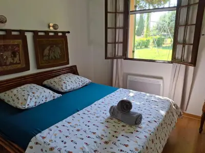 a bedroom with a bed with blue sheets and a window at Maison familiale Luberon in Lauris
