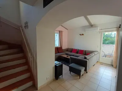 a living room with a couch and a staircase at Maison villa avec piscine et spa, 8 à 10 personnes in LʼIsle-sur-la-Sorgue
