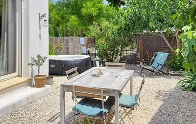 a patio with a wooden table and chairs at Maison Avec Jacuzzi in Mazan