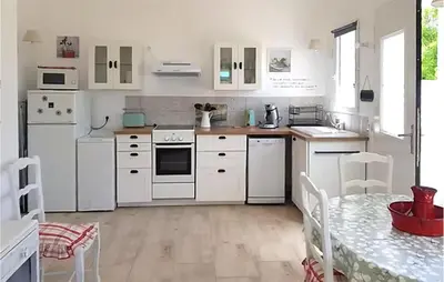 a white kitchen with white appliances and a table at Maison Avec Jacuzzi in Mazan