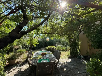 a table and chairs in a garden under a tree at La Maison du Petit Hérisson de 170 m2 avec jardin parking accueil de 6 personnes barbecue in Aix-en-Provence