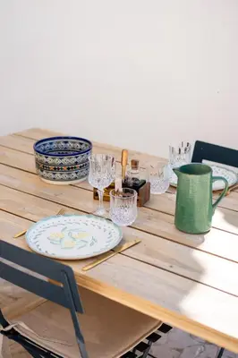 a wooden table with plates and glasses on it at Villa Augustine - Maison classée 5 étoiles avec piscine à Aix en Provence in Aix-en-Provence