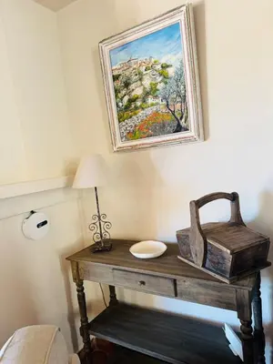 a table with a lamp and a painting on the wall at Charming house in the village center of Venasque in Venasque