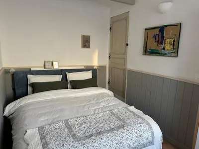 a bedroom with a bed and a painting on the wall at Maison au Cœur de Isle-sur-la-Sorgue in LʼIsle-sur-la-Sorgue