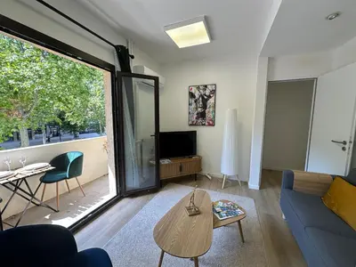 a living room with a blue couch and a tv at L'étape Aixoise - appartement climatisé terrasse centre ville Rotonde cours Mirabeau allées provençales in Aix-en-Provence