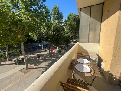 a balcony with two tables and benches on a building at L'étape Aixoise - appartement climatisé terrasse centre ville Rotonde cours Mirabeau allées provençales in Aix-en-Provence