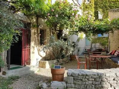 a garden with a table and chairs and a red door at Charming house in Provence, 2 to 10 people in Saignon
