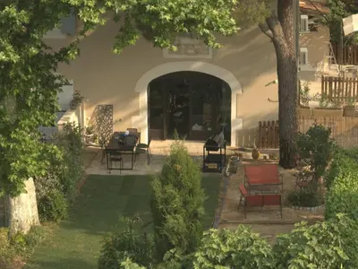 a house with a patio with chairs and a tree at Gîte dans un mas Provençal - L'Oustalet in Saint-Andiol