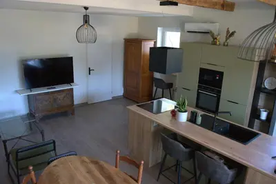 a living room with a kitchen with a table and a television at Gîte dans un mas Provençal - L'Oustalet in Saint-Andiol