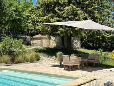 a patio with a table and an umbrella next to a pool at Le Bastidon in Caseneuve