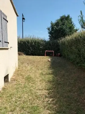 a grassy yard with a building and a hedge at L infiniment zen in Caromb