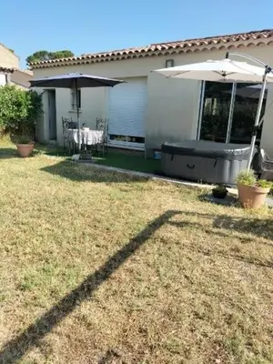 a yard with a house with an umbrella and a chair at L infiniment zen in Caromb