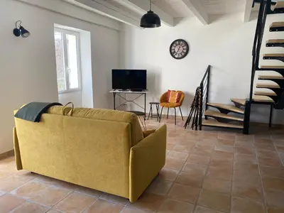 a living room with a yellow couch and a tv at Les Tilleuls in Bonnieux
