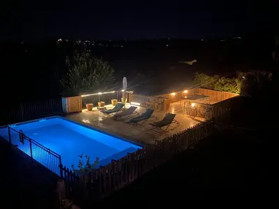 a swimming pool at night with chairs and lights at Les terrasses des pourquiers in Gordes