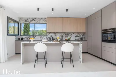 a kitchen with two white stools at a counter at Domaine Bellevue Ste-Victoire View Pools & Cinema in Le Puy-Sainte-Réparade