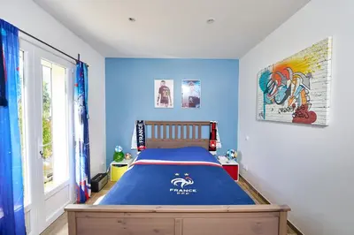 a bedroom with a bed with a blue wall at Maison au calme proche Mont Ventoux et Luberon in Malemort-du-Comtat