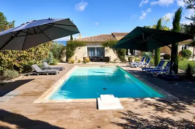 a swimming pool with two umbrellas and a house at Maison au calme proche Mont Ventoux et Luberon in Malemort-du-Comtat