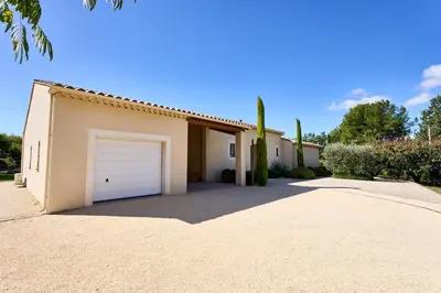 a house with a garage door in a driveway at Maison au calme proche Mont Ventoux et Luberon in Malemort-du-Comtat