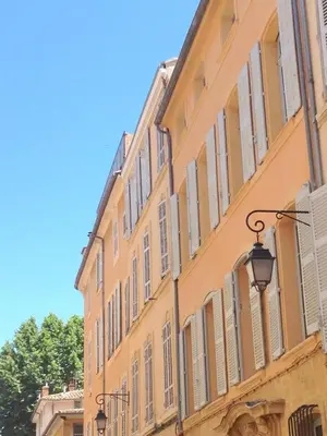 a yellow building with shuttered windows and a street light at Large studio with terrace and air conditioning in Aix-en-Provence