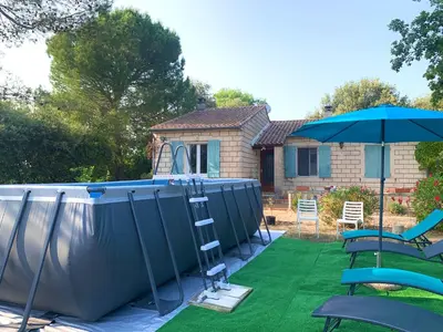 a garden with a ladder and an umbrella and chairs at La maison aux oiseaux - Luberon in Oppède