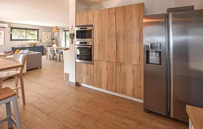 a kitchen with wooden cabinets and a stainless steel refrigerator at Maison Avec Piscine Privée in Monteux