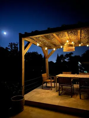 a pergola with a table and chairs on a deck at night at Casa Bohemia, piscine privée proche Aix en Provence in Ventabren