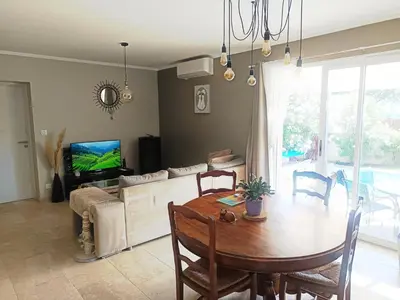 a living room with a dining room table and a tv at Villa KAMARO in LʼIsle-sur-la-Sorgue