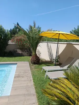 two lounge chairs and an umbrella next to a pool at Villa KAMARO in LʼIsle-sur-la-Sorgue