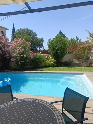 a swimming pool with a table and chairs next to it at Villa KAMARO in LʼIsle-sur-la-Sorgue