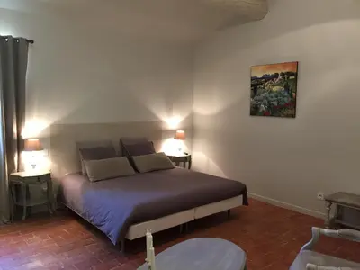 a bedroom with a bed with a painting on the wall at La Rivayne in Lourmarin