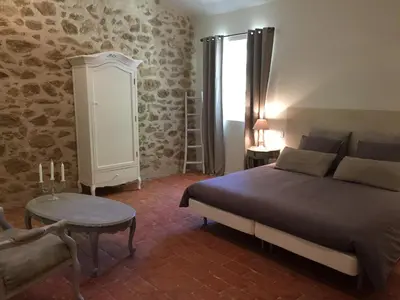 a bedroom with a bed and a table and a chair at La Rivayne in Lourmarin