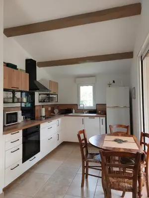 a kitchen with white cabinets and a table with chairs at La Clemensane in Lacoste