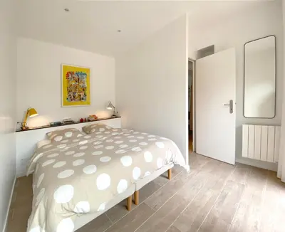 a white bedroom with a bed and a mirror at Chez Pascal et Marion in La Tour-dʼAigues