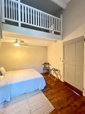 a bedroom with a white bed and a staircase at Authentique et paisible maison de village in Bédoin