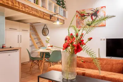 a vase with flowers on a table in a living room at Studio Mezzanine Cosy in Aix-en-Provence