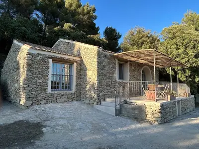 a stone house with a large window and a porch at Bastidon provençal entièrement rénové et climatisé in Vaugines