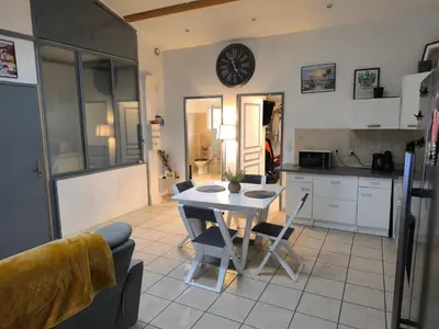 a kitchen with a table and chairs and a clock on the wall at Appartement provençal in Vedène