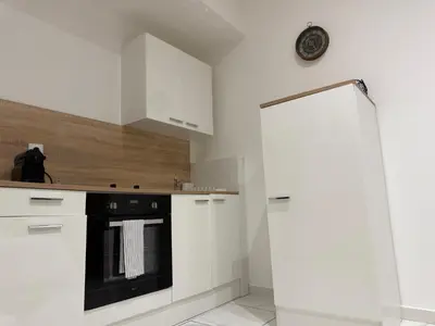 a kitchen with white cabinets and a black oven at Bonpas Appart Hotels in Avignon