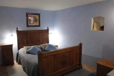 a bedroom with a wooden bed with blue pillows at Chambres d'Hôtes Istrane in Rustrel