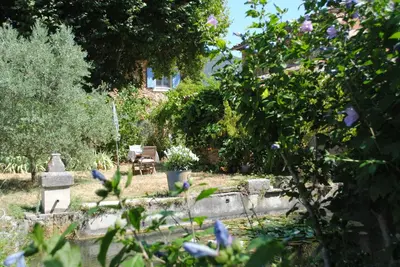 a garden with a grave and flowers in front of a house at Chambres d'Hôtes Istrane in Rustrel