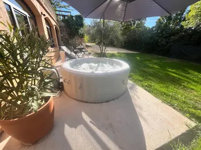 a large hot tub sitting next to two potted plants at Aix-en-Provence, Cosy studio au calme de la campagne avec Spa et Clim in Aix-en-Provence
