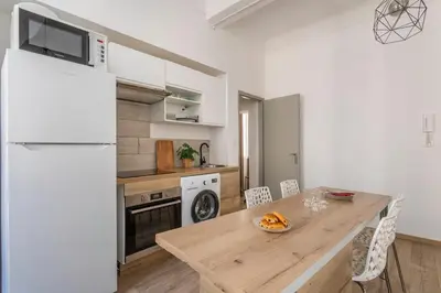 a kitchen with a wooden table and a white refrigerator at Central studio, perfect for discovering Aix on foot in Aix-en-Provence