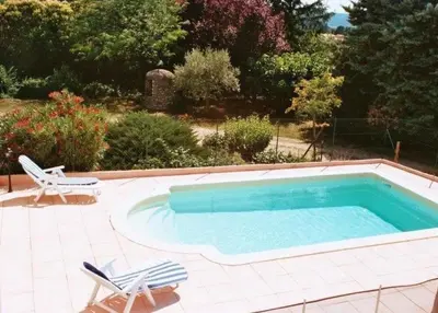 a swimming pool with two chairs and a table at Ferme au pied du luberon in Lourmarin