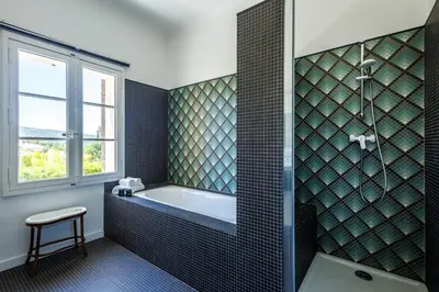 a bathroom with a bath tub and a window at Villa du Val - Welkeys in Aix-en-Provence