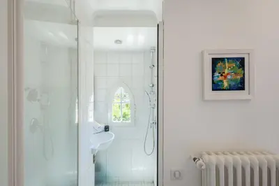 a white bathroom with a shower and a window at Villa du Val - Welkeys in Aix-en-Provence