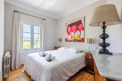 a bedroom with a white bed with a lamp and a window at Villa du Val - Welkeys in Aix-en-Provence