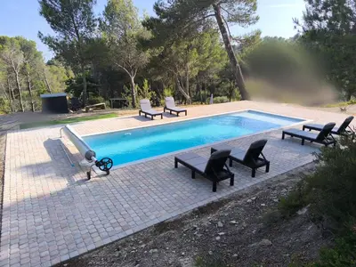 a swimming pool with chaises and chairs around it at Evasion sous les pins in Aurons