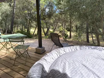 a bed and a table and chairs on a wooden deck at Evasion sous les pins in Aurons