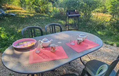 a picnic table with two chairs and a table with tea sets on at Maison Avec Piscine in La Tour-dʼAigues
